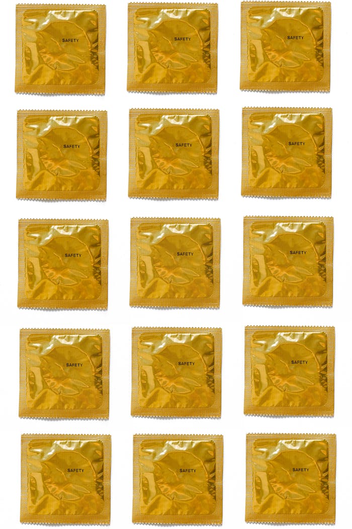 services-04 A collection of gold condom packages arranged on a white background for health and safety promotion.